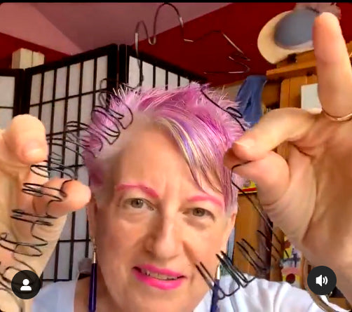 Artist Anne Nordhaus-Bike holding spiral wire "hair" from Wirehaired Me multimedia sculpture