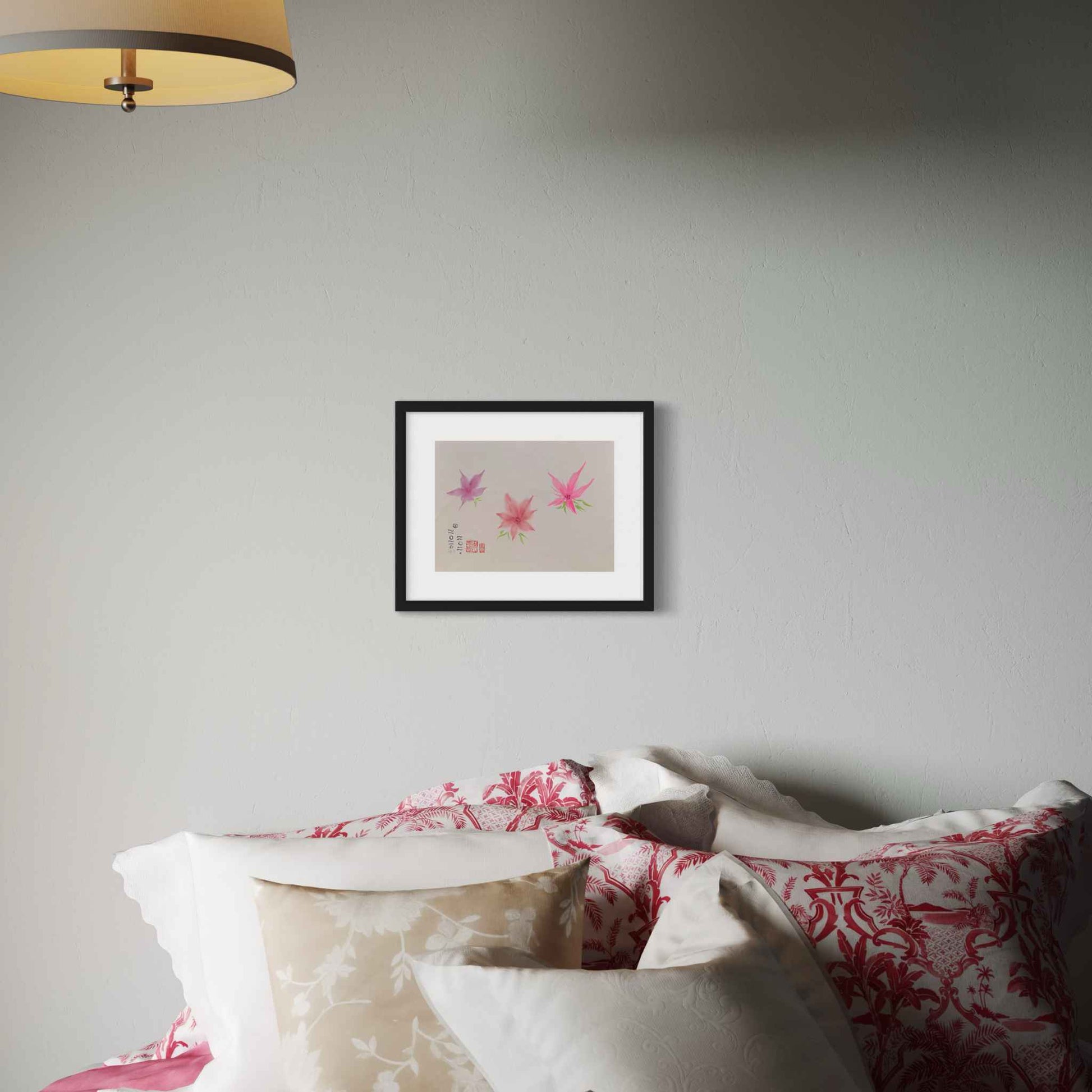 Three little bright pink flowers watercolor, displayed above bed with red and white floral sheets