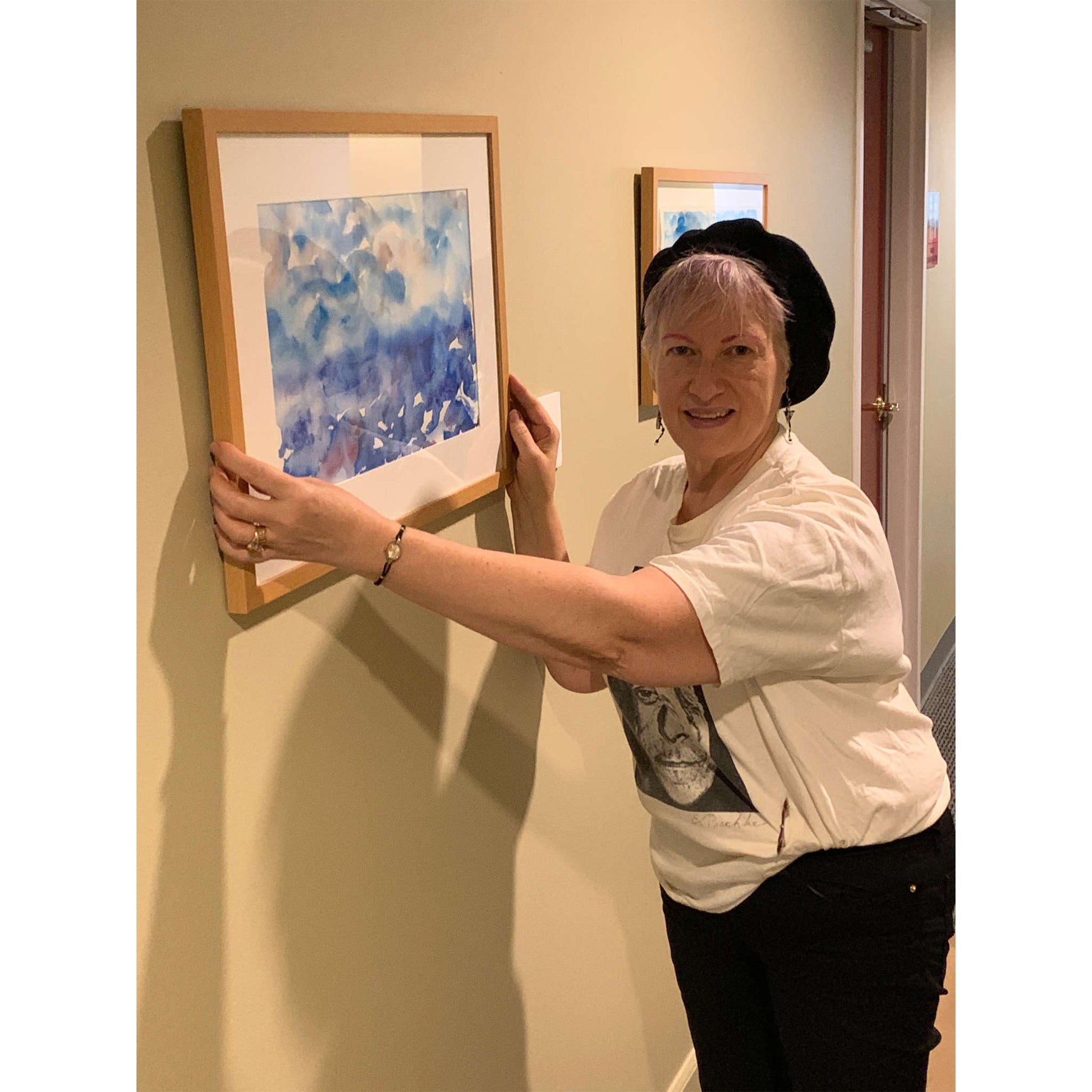 Artist Anne Nordhaus-Bike in black and white with beret, installing Deep Mystery framed watercolor