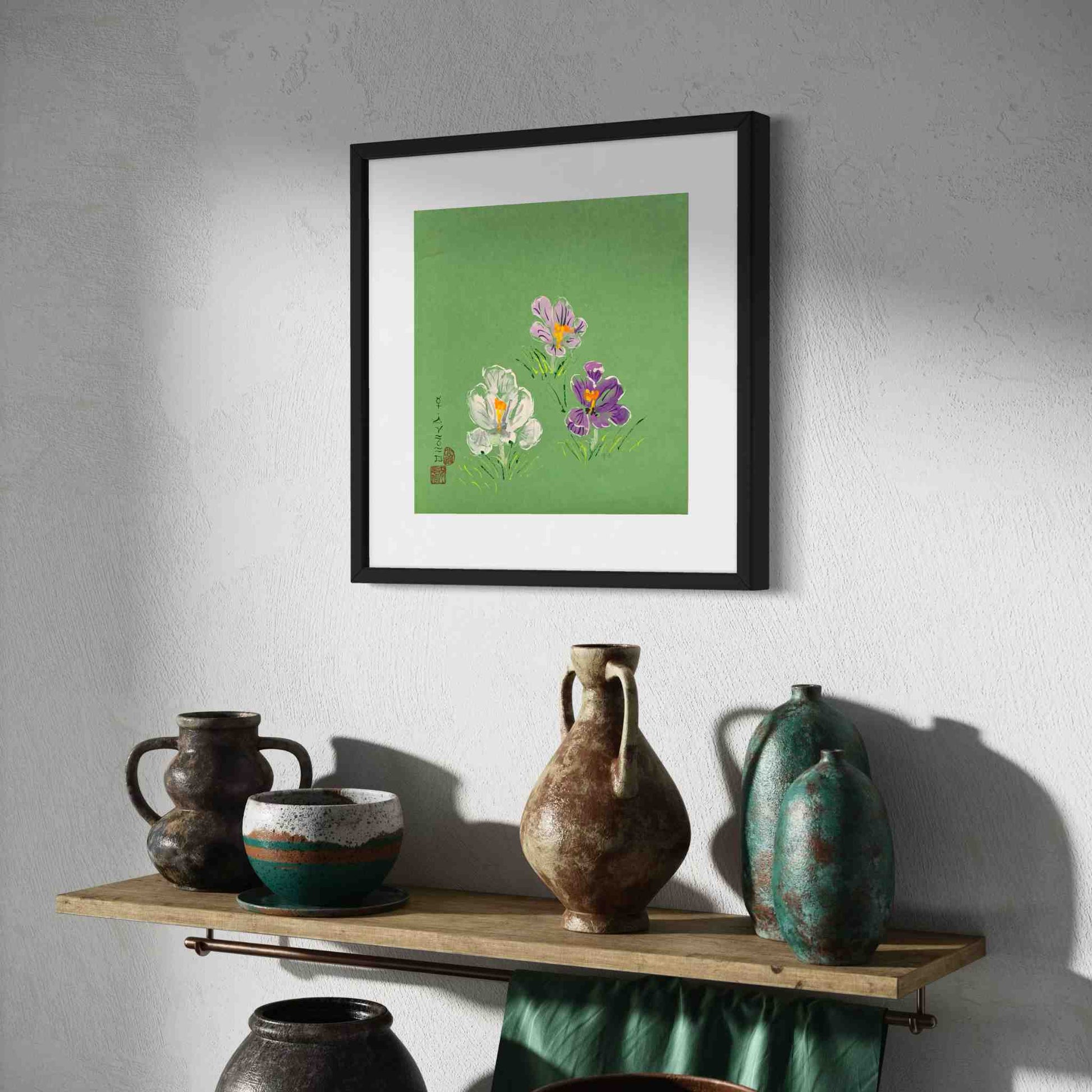 Three crocuses on jade green paper, framed watercolor, angled view above shelf with green pottery