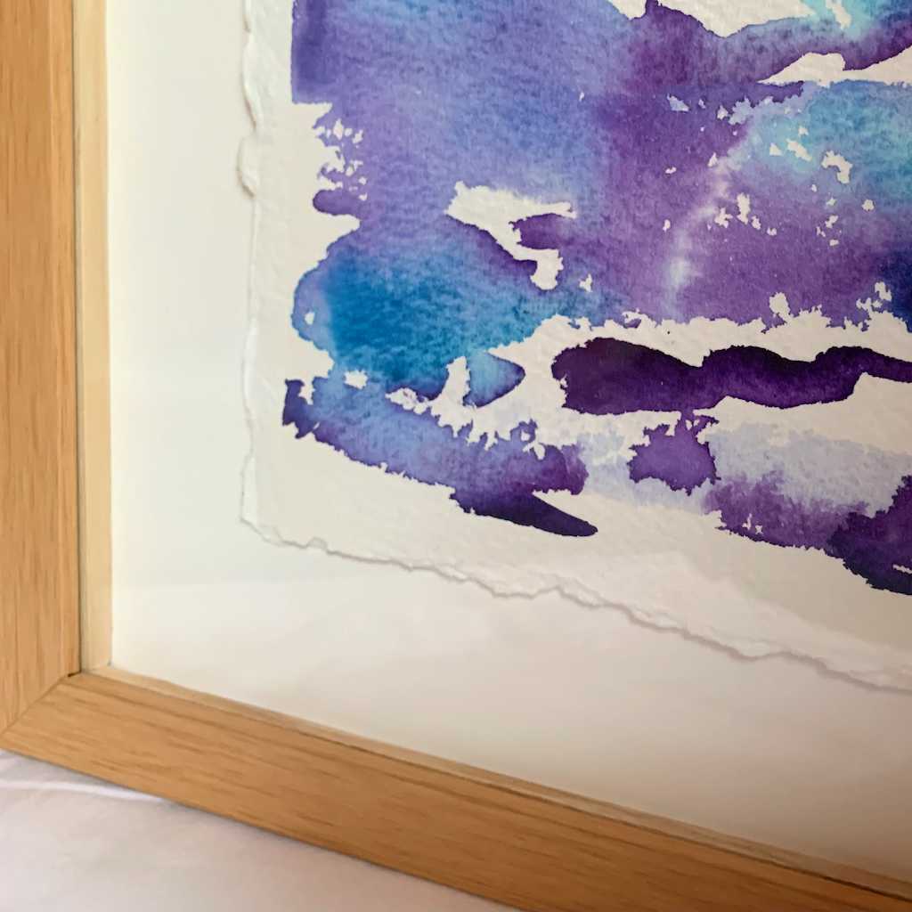 Float framed and matted Getting Ready blue and purple horizon watercolor landscape painting, closeup view showing lower left frame corner, painting's textured edges