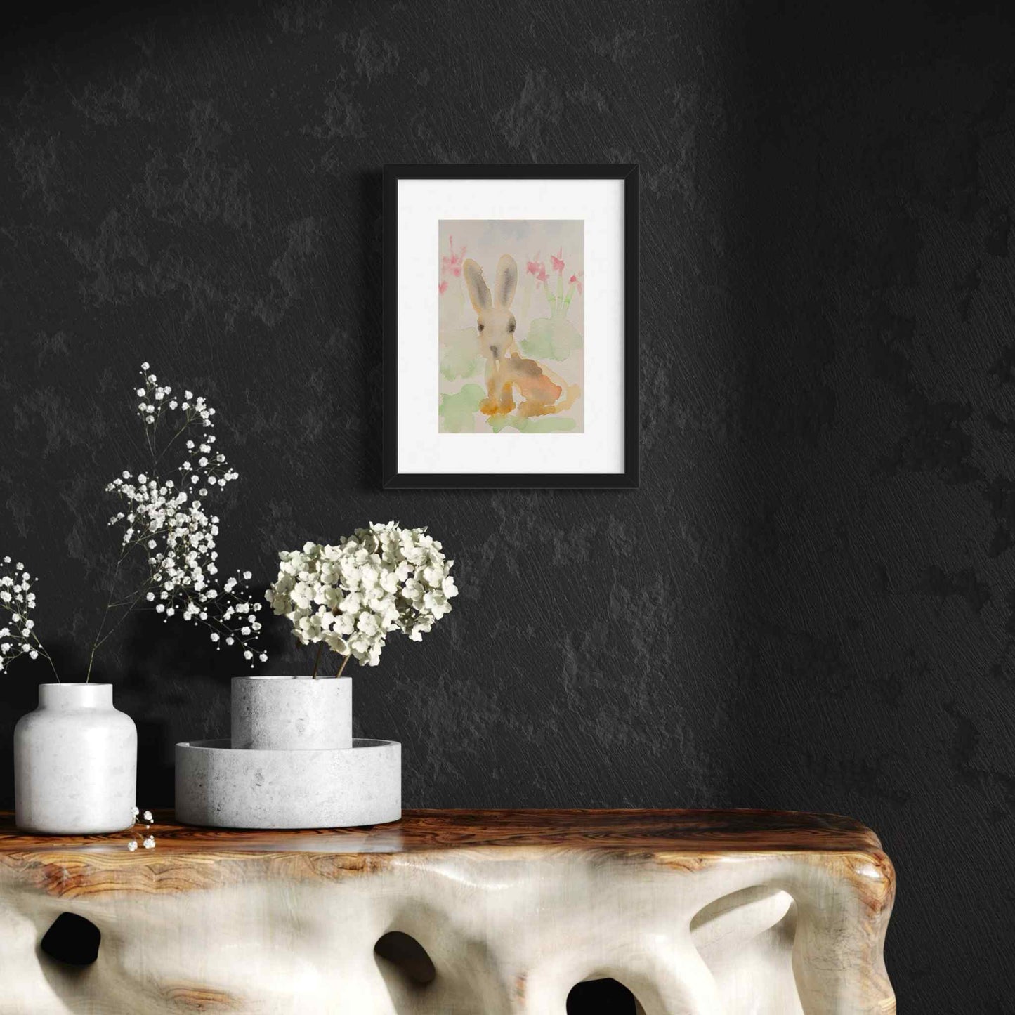 Pastel bunny rabbit watercolor painting, framed, in dramatic room with black wall and white flowers