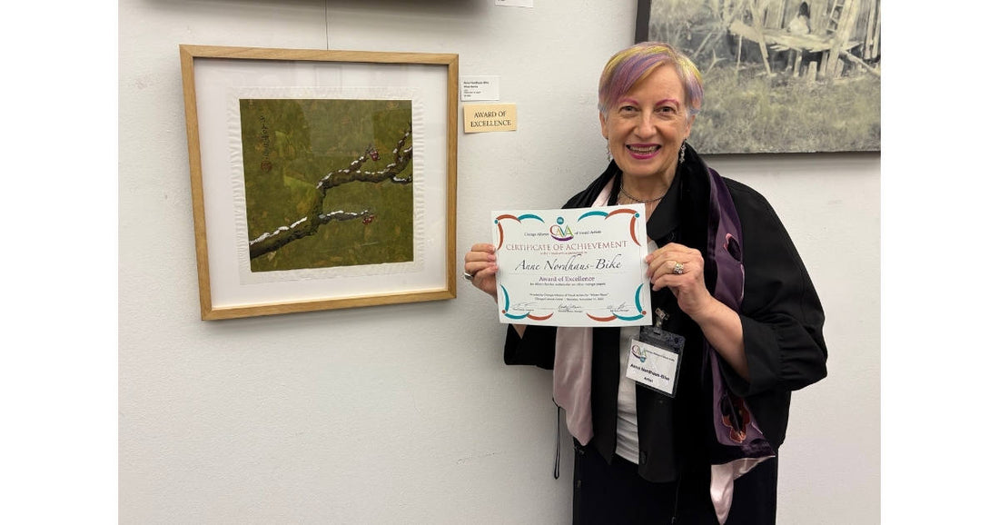 Artist holding award certificate next to her art at opening reception