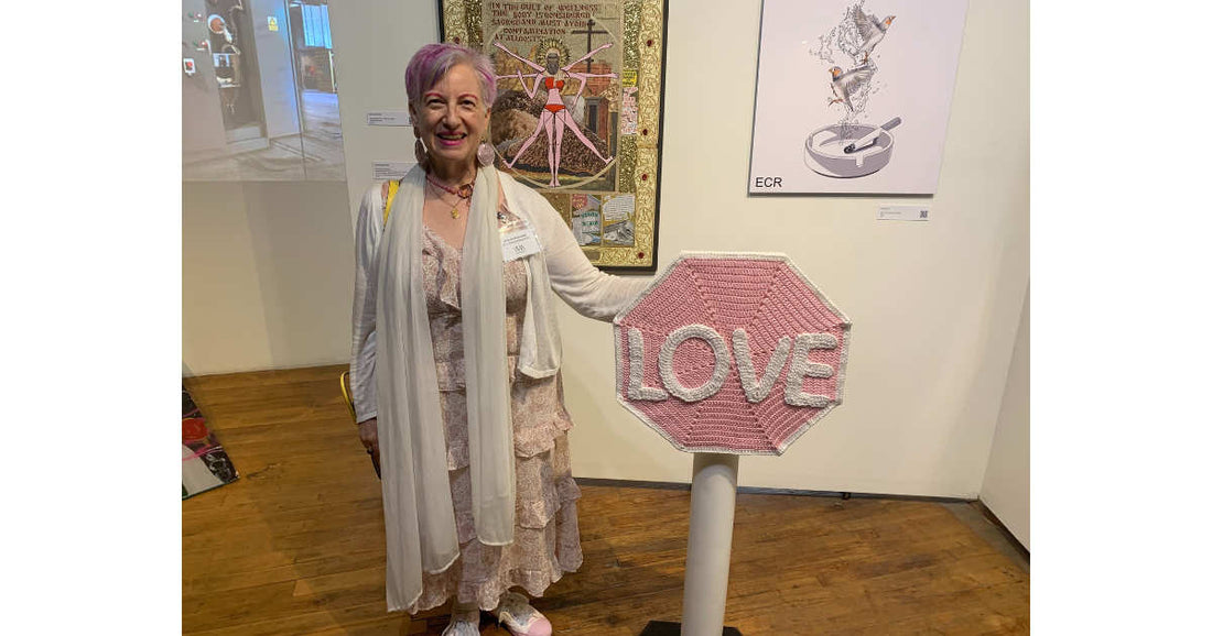 Woman standing next to a pink 'LOVE' sign sculpture in an art gallery