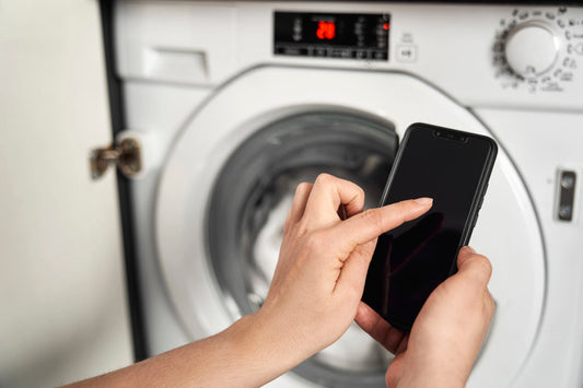 Person using a smartphone in front of a washing machine