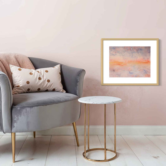 Mystic Stillness orange, blue, peach framed watercolor on pink wall by gray chair