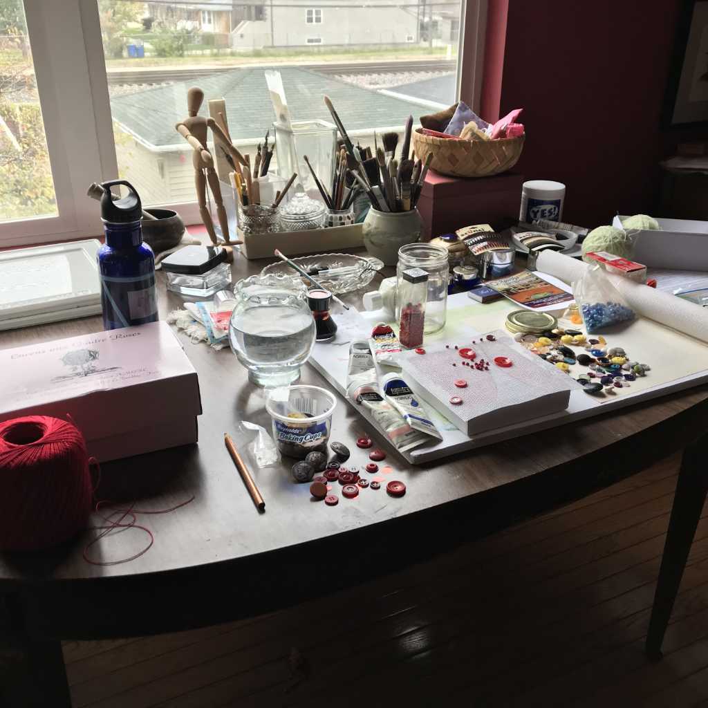 Creating mixed media piece Red Coat Remembered-Anne Nordhaus-Bike's studio with red thread, buttons